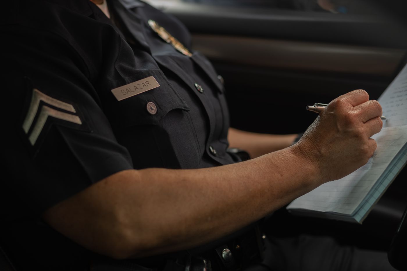 Police sergeant completing written documentation in a patrol vehicle