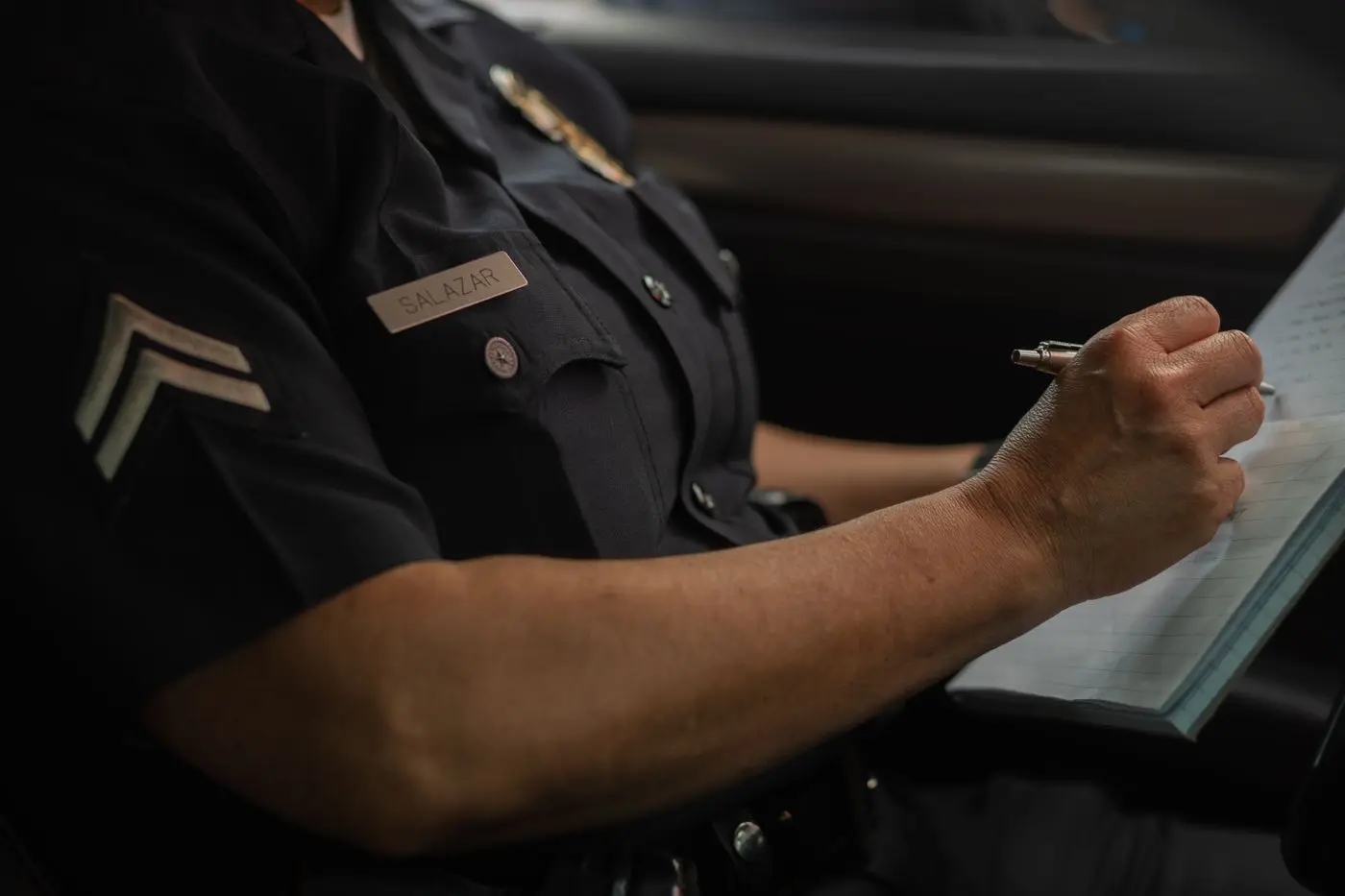 A police sergeant completing written documentation inside a patrol vehicle
